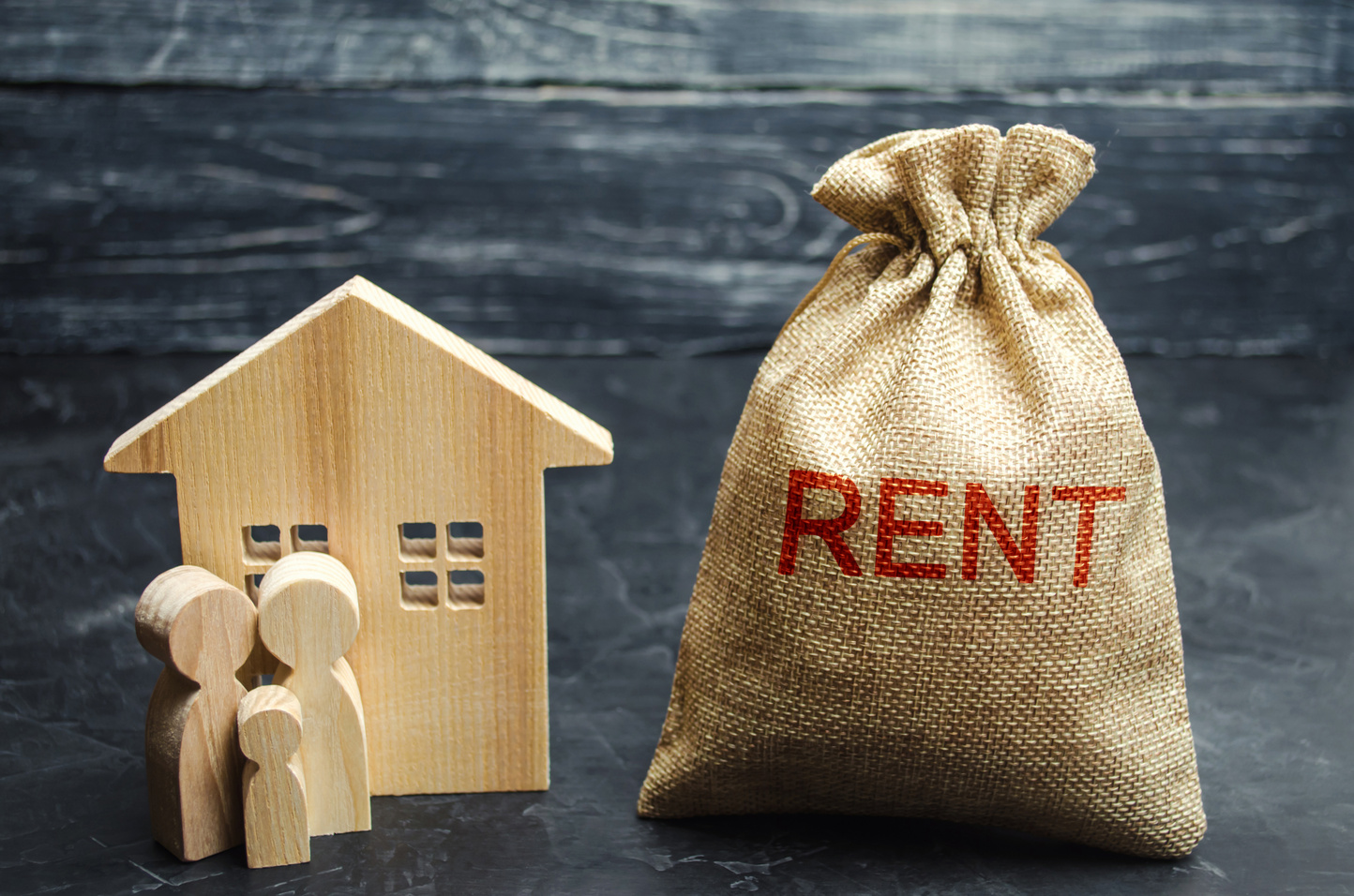 A bag with money and the inscription Rent and the family is standing near the house. Removable housing. Rental of property, apartments. services of a Real Estate Agent. affordable housing, rental prices.